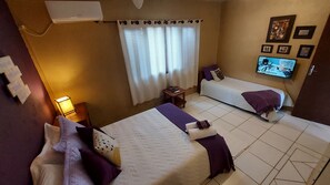 A hotel room with two beds, a TV, and a window with curtains. - Pousada Vistacalma (Imbituba)
