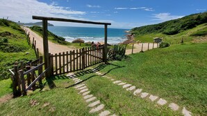 A wooden pathway leading to a beach with a clear view of the ocean. - Pousada Vistacalma (Imbituba)