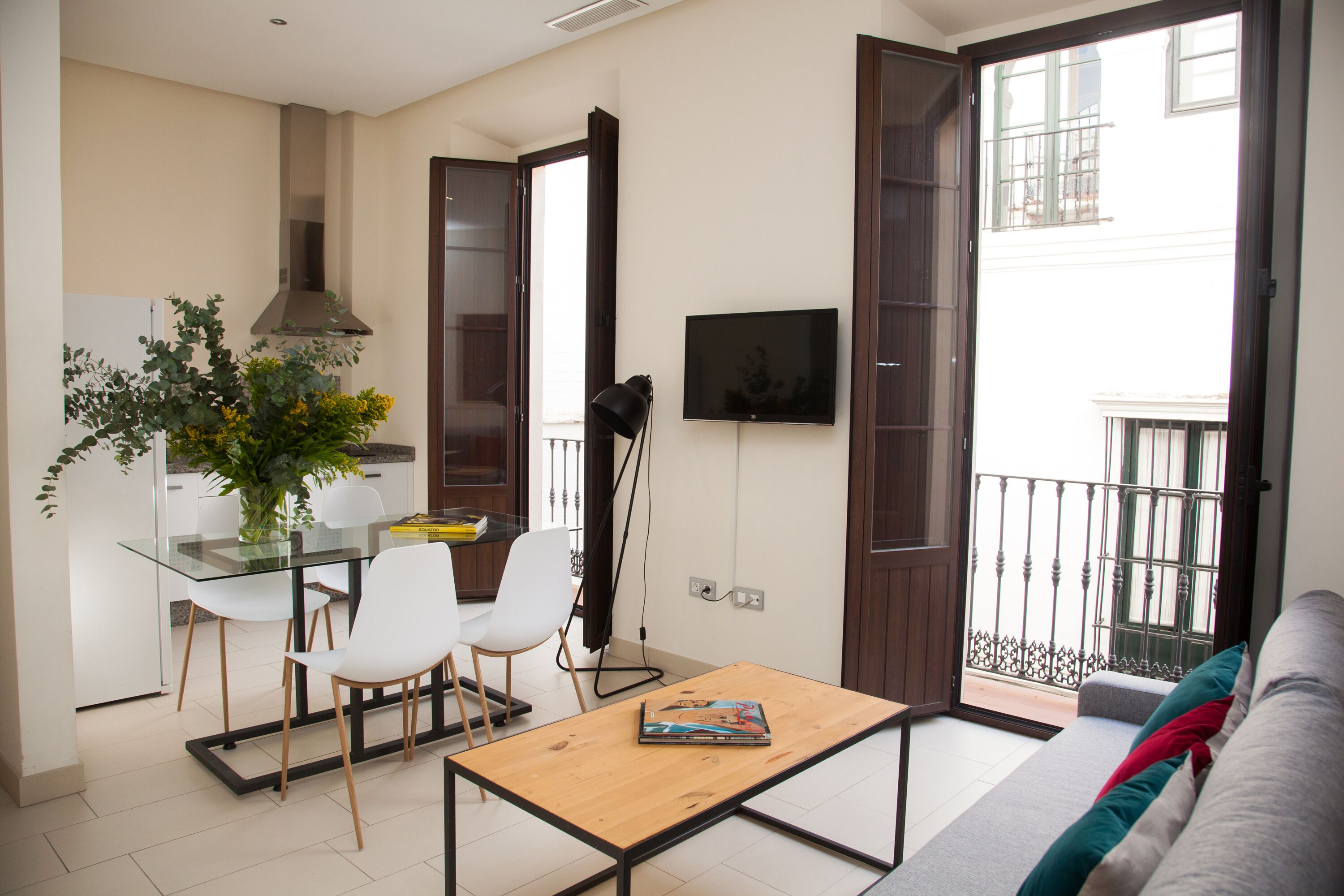 A modern living room with a sofa, a coffee table, and a dining area with chairs and a glass table.