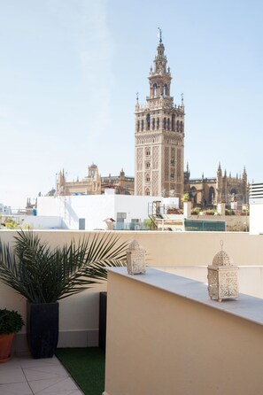 A rooftop terrace with a view of a historic building with a tall tower. - Guzman El Bueno Suites (Seville)