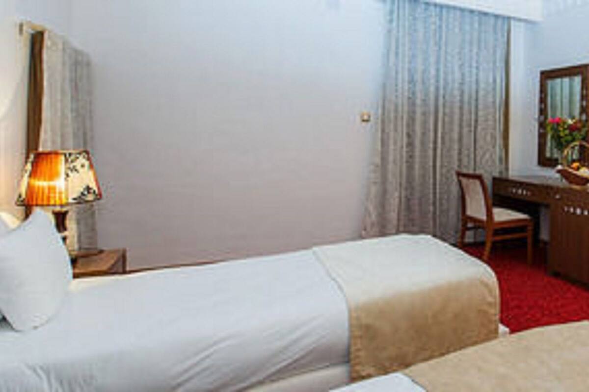 Une chambre d’hôtel avec un lit, un bureau, une chaise, une télévision et une moquette rouge.