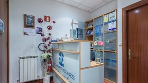 A reception desk with a sign for 'Dominipensiones Personal Consult'. There are framed certificates on the wall, a flower arrangement, and a fire extinguisher. - Pensión Ab Domini (San Sebastián)