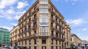 A multi-story building with balconies, a ground-floor entrance, and a visible sign. - Pensión Ab Domini (San Sebastián)