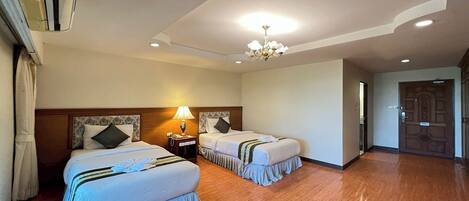 Habitación de hotel con dos camas, un candelabro y un equipo de aire acondicionado.