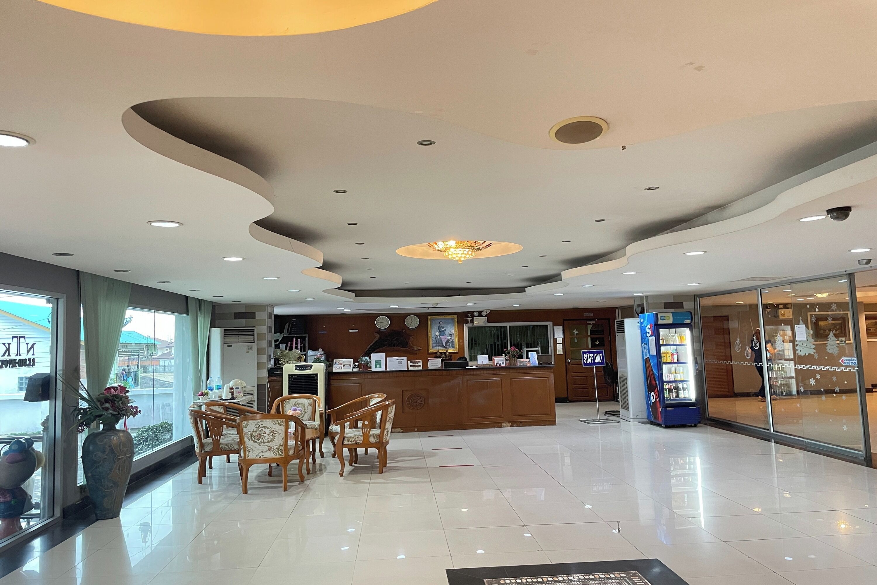 A hotel lobby with a reception desk, seating area, and vending machine.