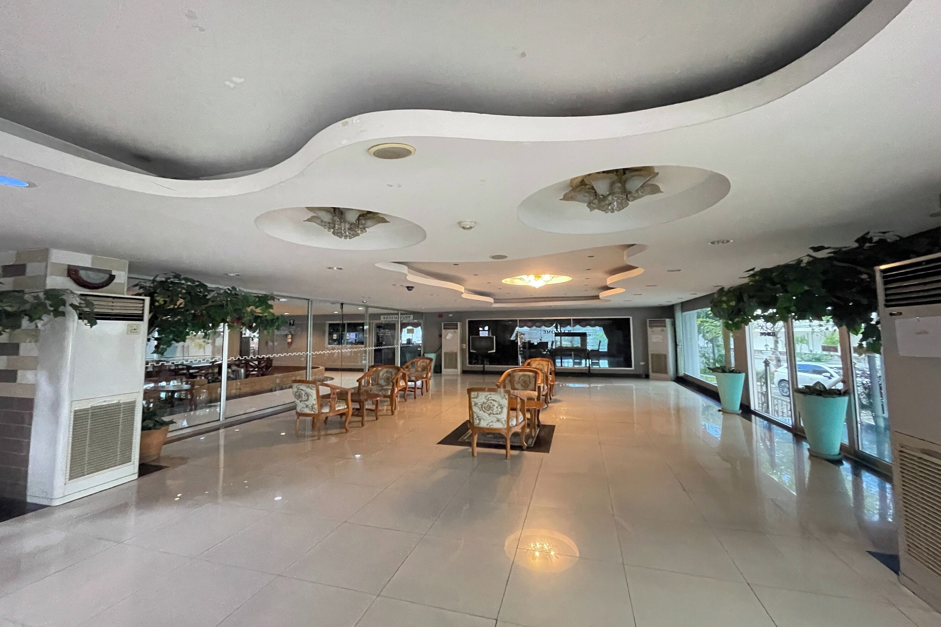 A spacious lobby with a modern ceiling design, seating area, and large windows.
