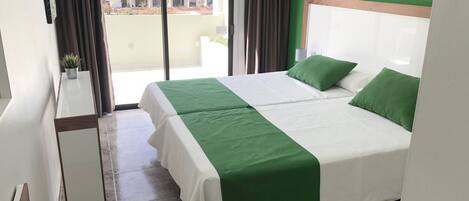 A hotel room with a bed, a small table, and a view of buildings outside.