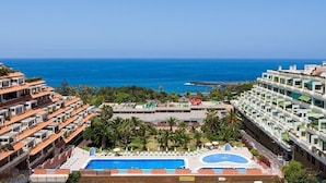 Un complexe hôtelier doté d’une grande piscine, de nombreux balcons et offrant une vue sur l’océan.
