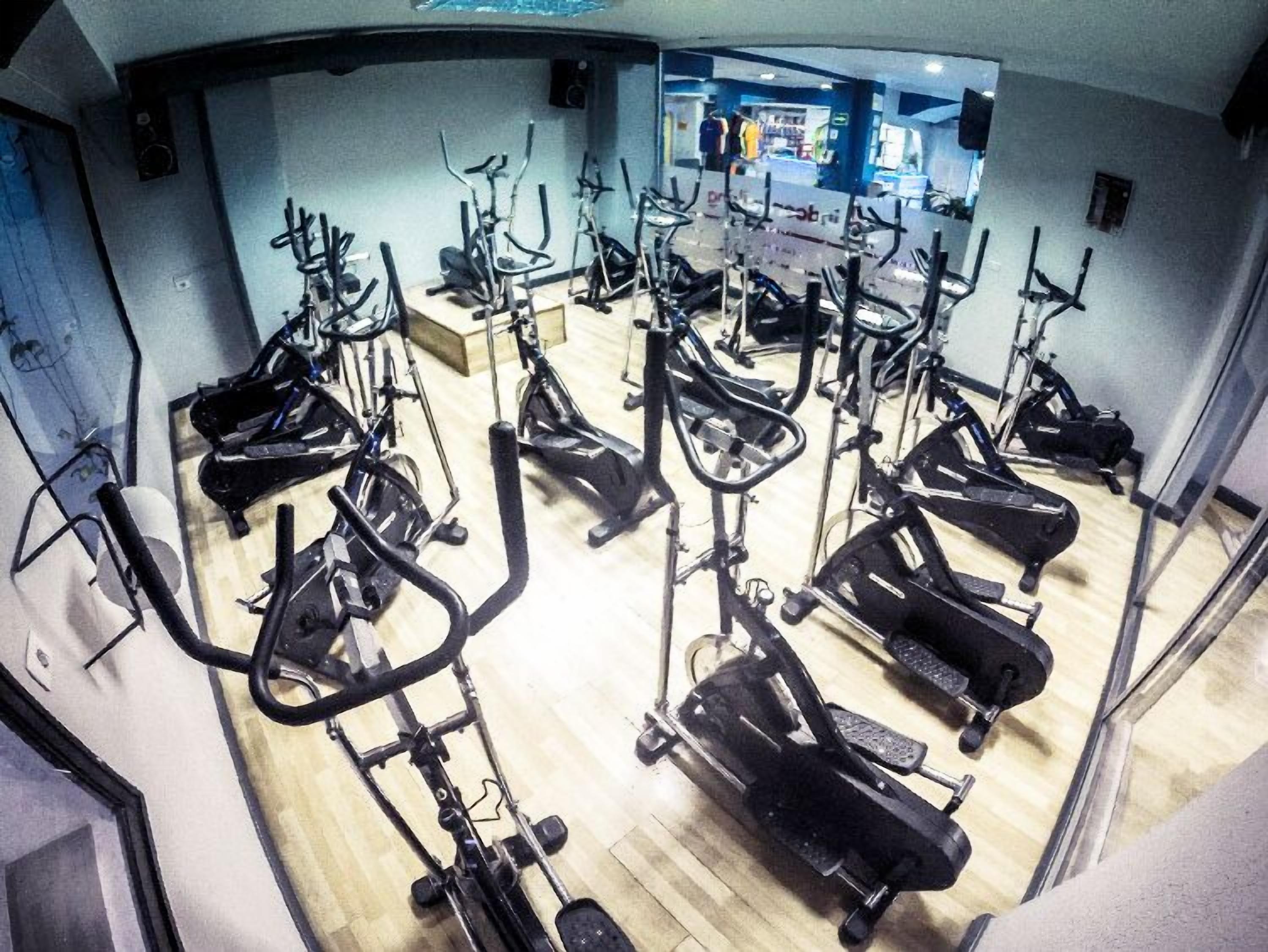Un centre de remise en forme doté de nombreux appareils de cardio, notamment des elliptiques et des tapis de course, disposés en rangées.