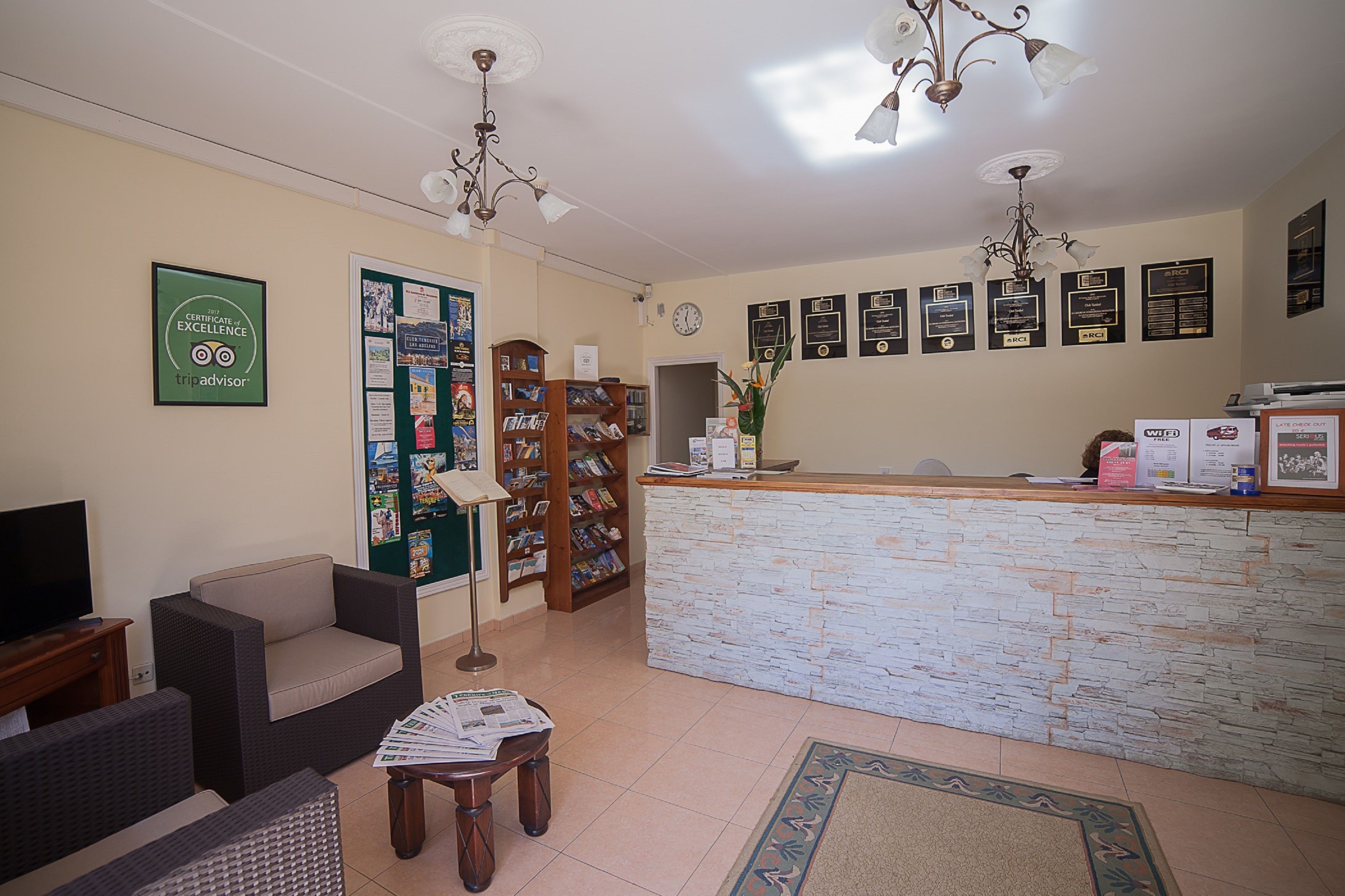A reception area with a stone counter, a clock, and a wall decorated with certificates.