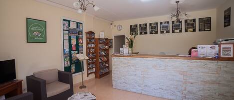 A reception area with a stone counter, a clock, and a wall decorated with certificates.