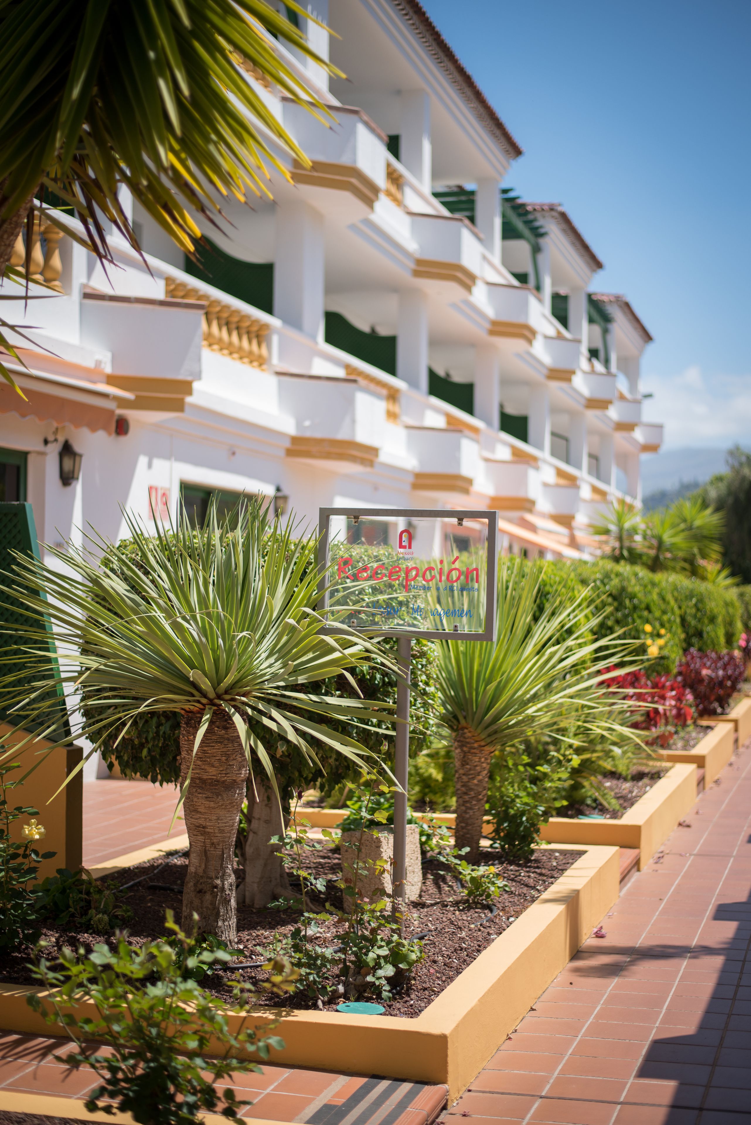 Un hotel con fachada blanca, balcones y un letrero en español.