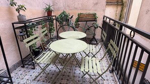 A small outdoor seating area with two round tables and four chairs, surrounded by a metal fence. - Le Globe (Paris)