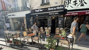 An outdoor seating area with tables and chairs, a bar, and a restaurant named 'Hotel du Globe'. - Le Globe (Paris)