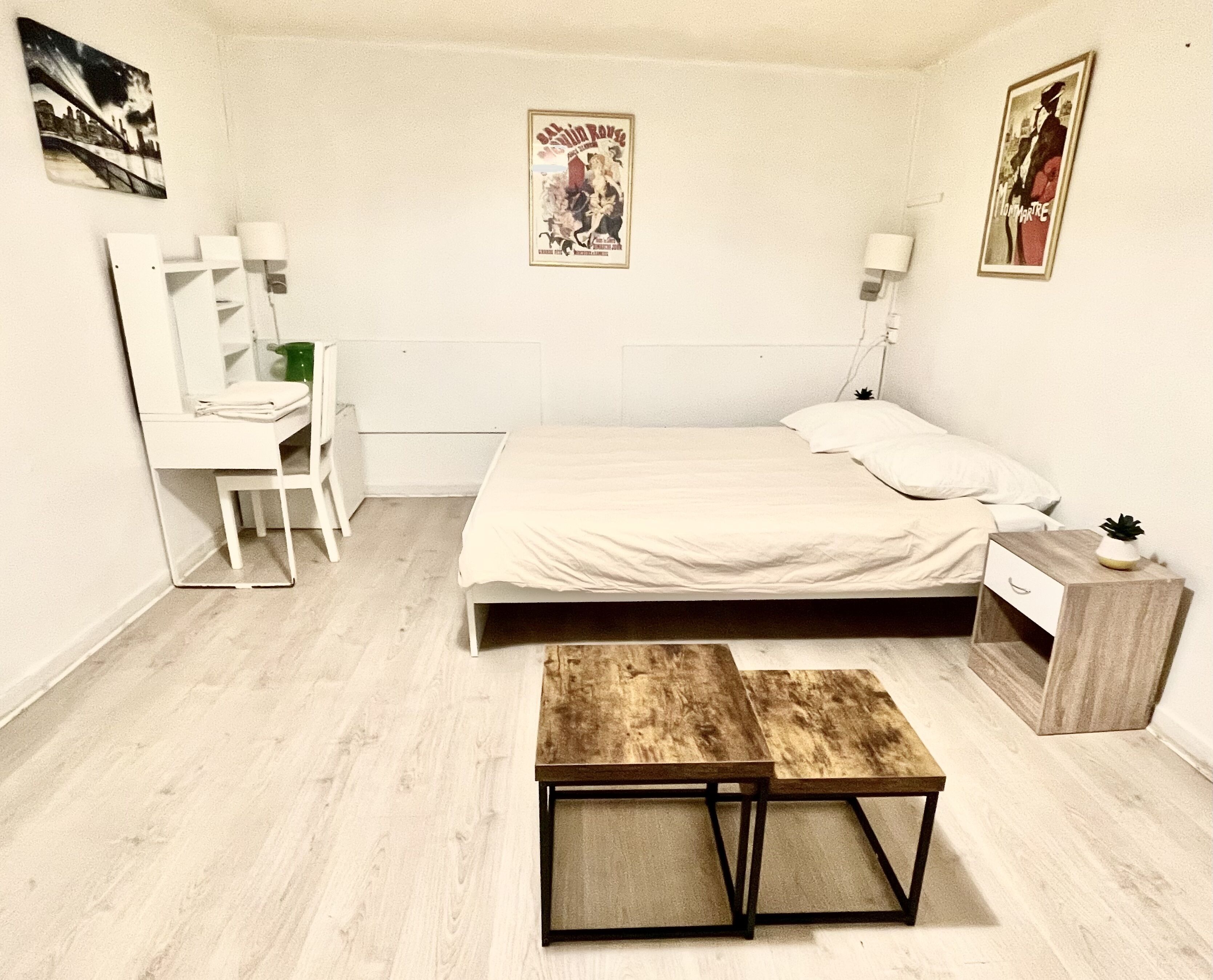A bedroom with a bed, a wooden bench, a desk, and a chair.