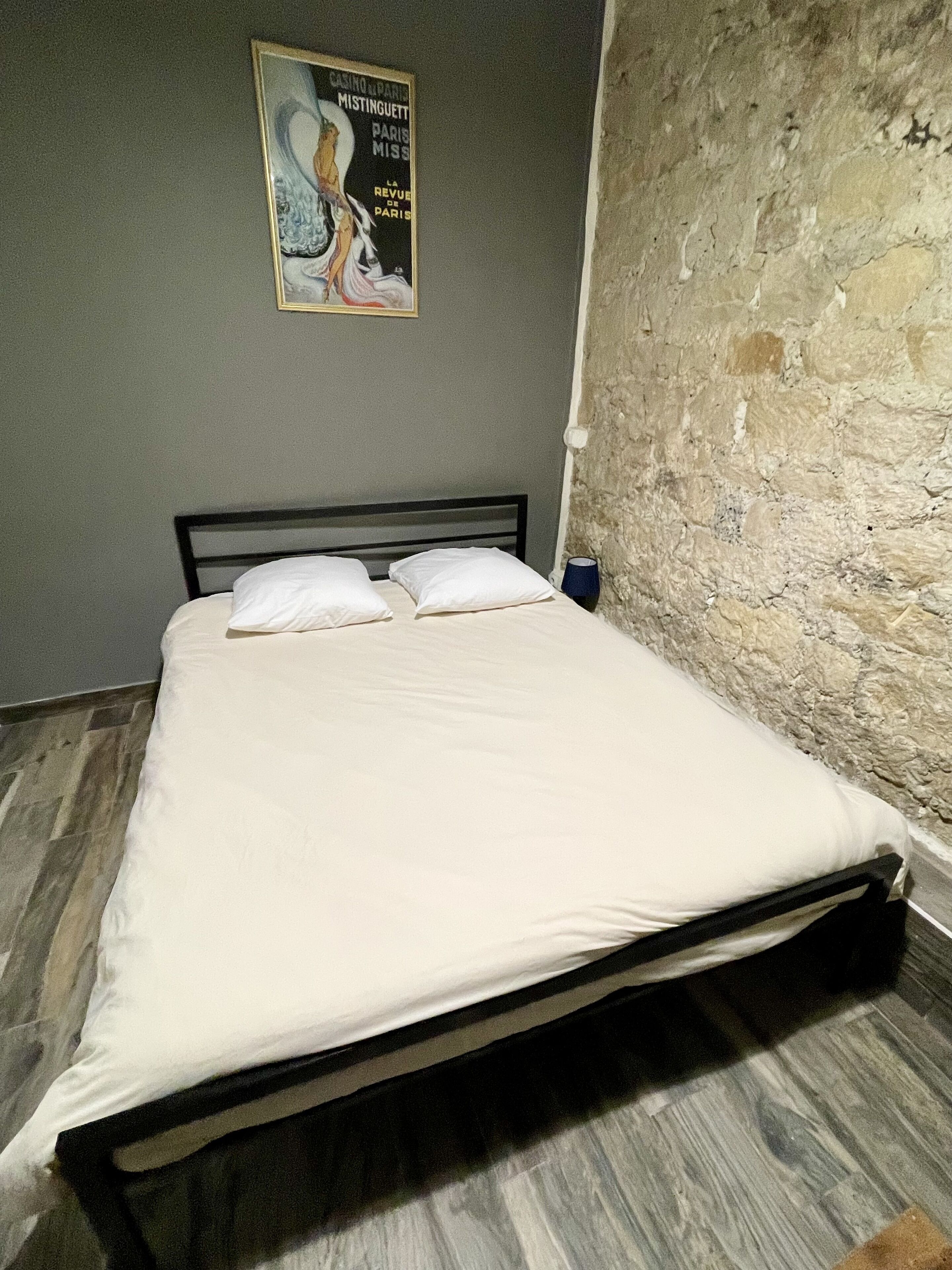 A bed in a room with a stone wall and a poster on the wall.