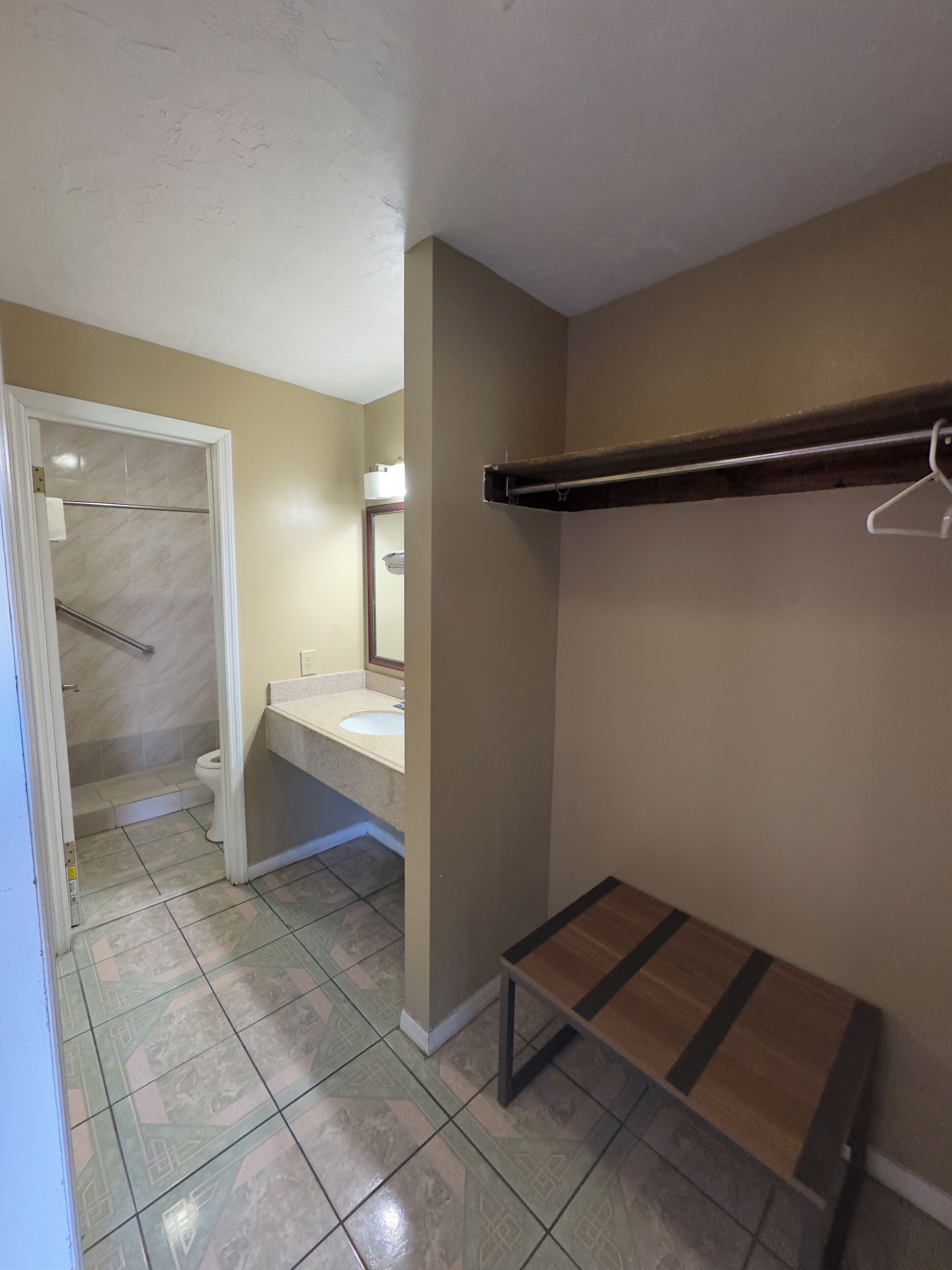A bathroom with a shower, toilet, sink, and a towel rack.