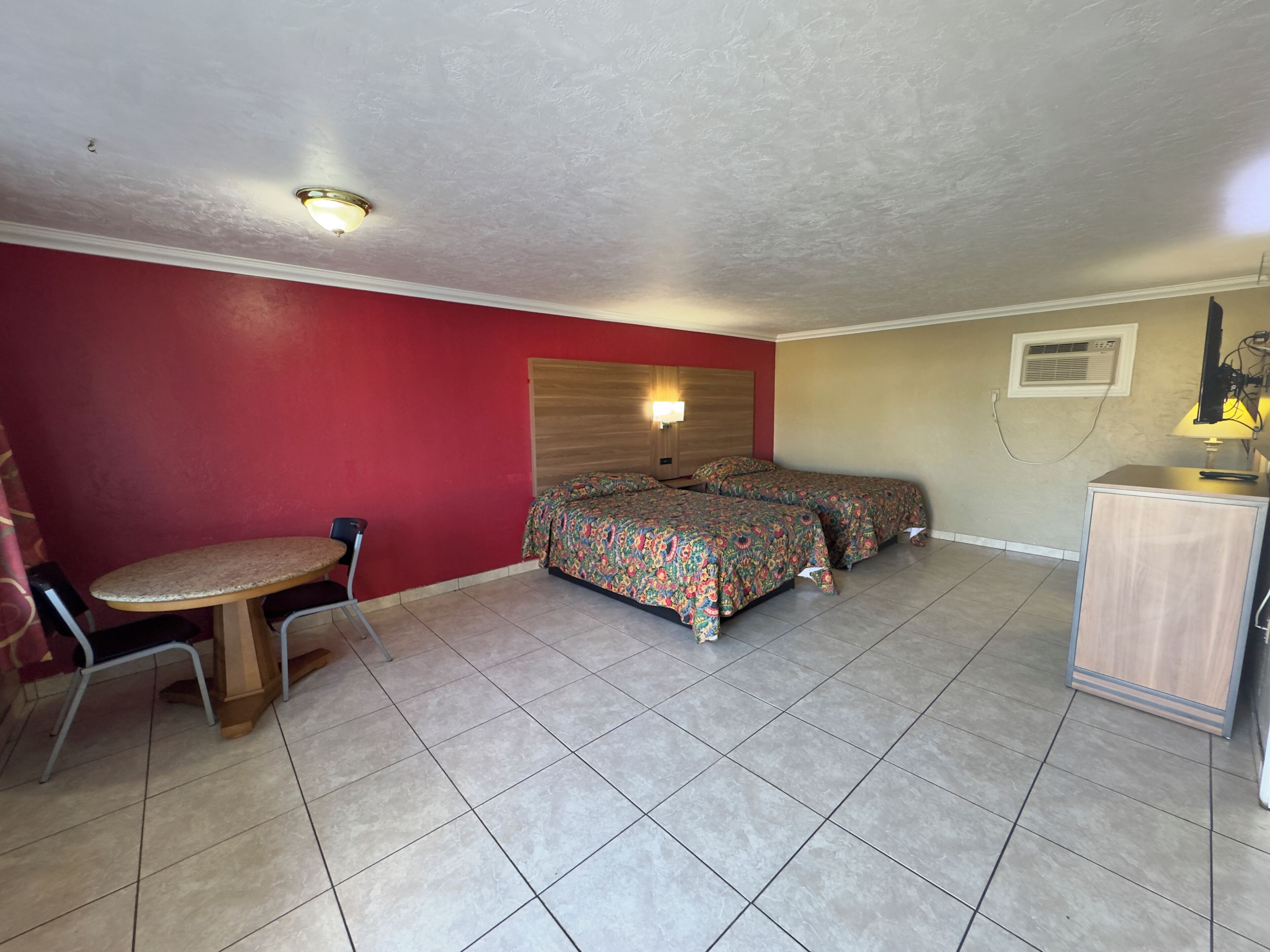 A room with a bed, a desk, a chair, and a lamp.