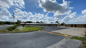 A motel with a parking lot and a grassy area. - Economy Inn (Arcadia)