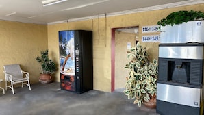 A reception area with a vending machine, a water dispenser, a potted plant, and a chair. - Economy Inn (Arcadia)