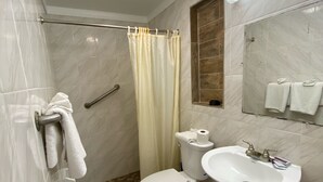 A bathroom with a shower, toilet, sink, and towel rack. - Economy Inn (Arcadia)