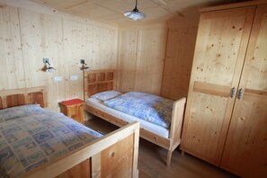 A wooden cabin with two bunk beds, a small table, and a wardrobe. - Ferienwohnungen am Berg - Almhütte Alfen (Innervillgraten)
