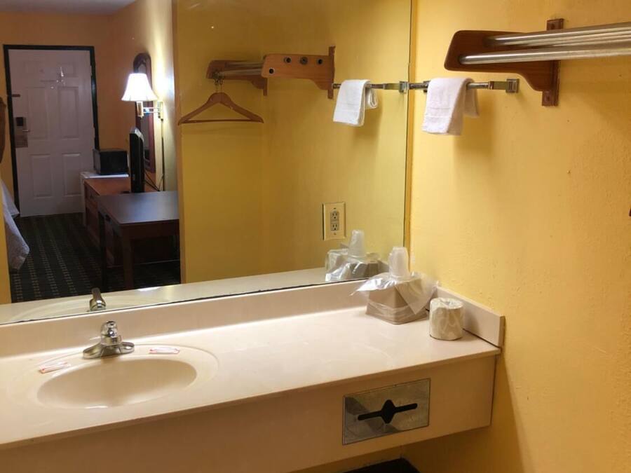 Une salle de bain d’hôtel avec un grand miroir, un lavabo et un porte-serviettes.