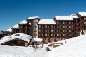 A multi-story hotel with balconies and a snow-covered roof.