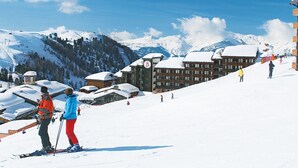 A ski resort with snow-covered slopes, a lodge with multiple floors, and a mountain backdrop.