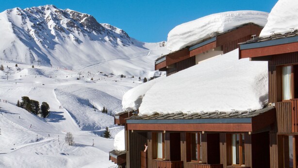 A snow-covered mountain with a wooden building featuring balconies and windows.