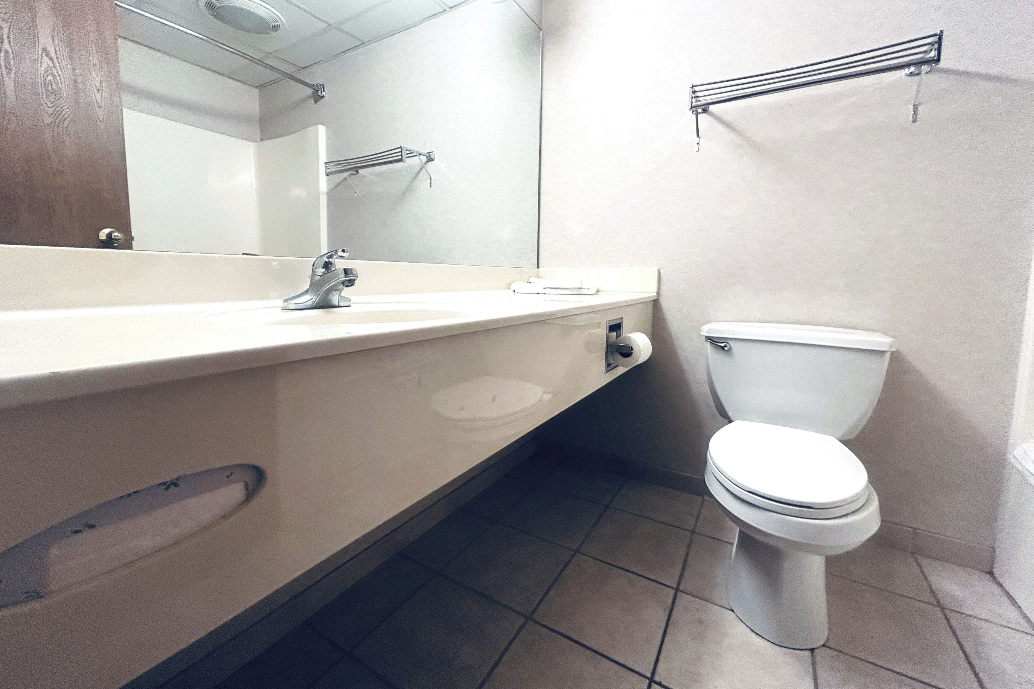 A bathroom with a white sink, mirror, and toilet.