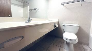 Un baño con lavamanos, espejo e inodoro blancos.
