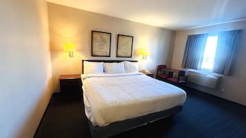 Una habitación de hotel con una cama grande, dos lámparas de noche, un mapa en la pared, una silla y una ventana con cortinas.
