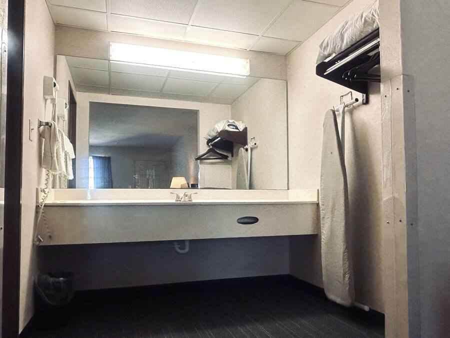 A bathroom with a mirror, sink, towel rack, and a shower area.
