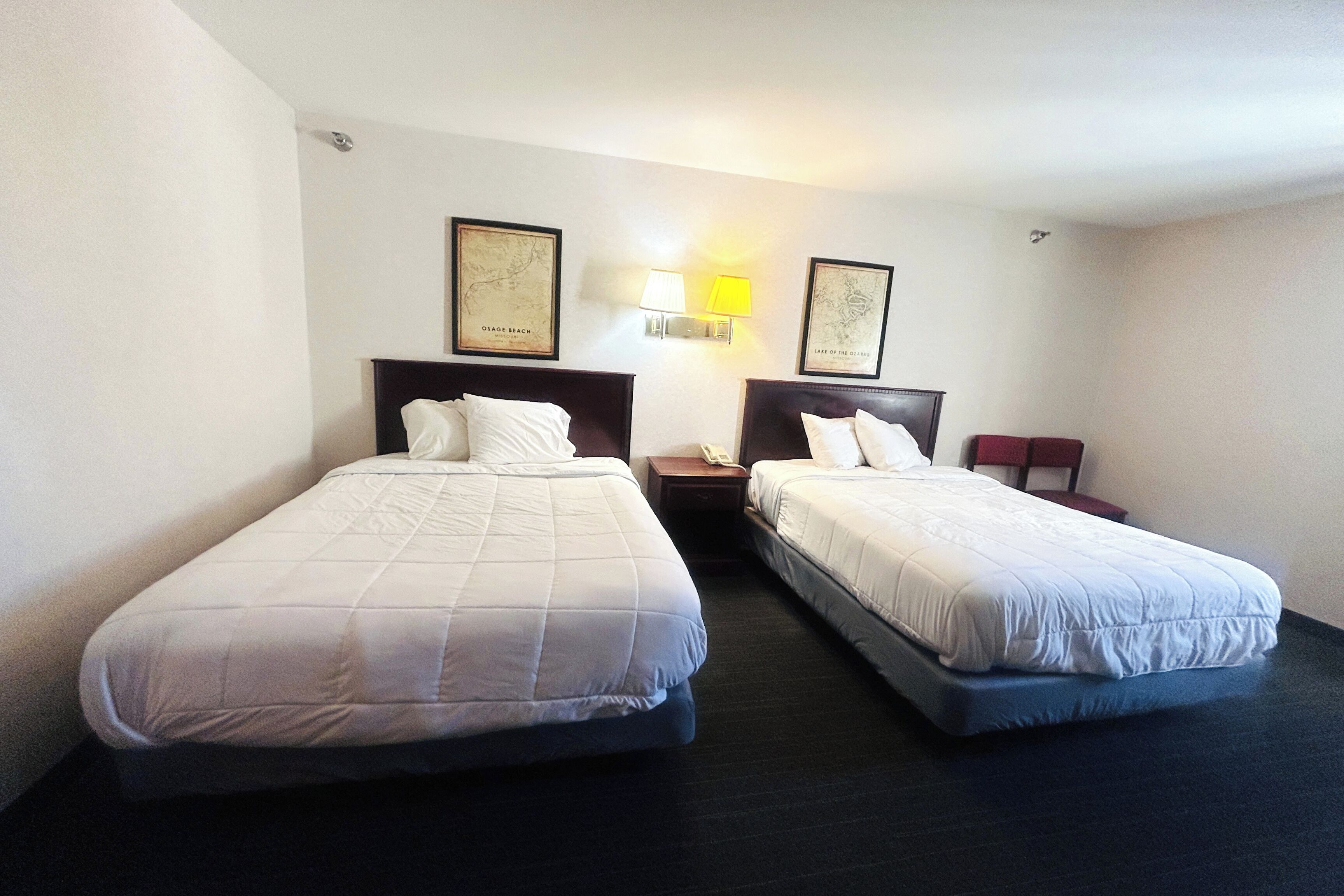Two single beds with headboards, a bedside table with a lamp, and a framed map on the wall.