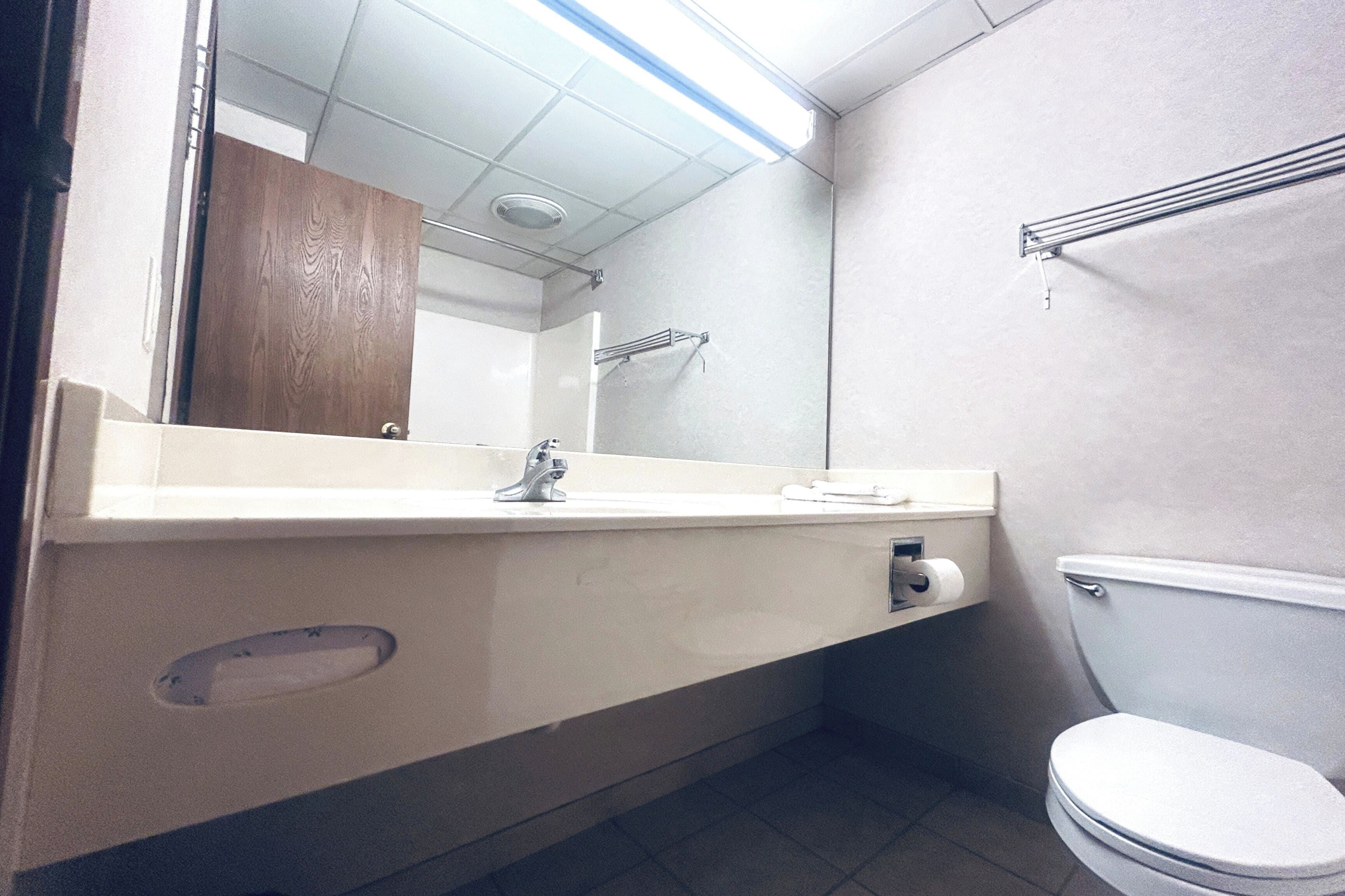 A bathroom with a white sink, mirror, and toilet.