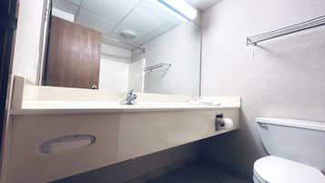A bathroom with a white sink, mirror, and toilet.