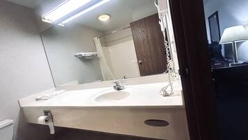 A bathroom with a white sink, a mirror, a shower curtain, and a towel rack.