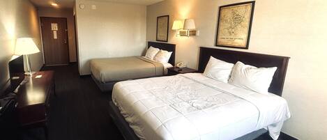 Una habitació d'hotel amb dos llits, un escriptori, una làmpada, un telèfon i un mapa a la paret.