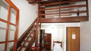 A room with a wooden staircase, a bed, a chair, and a wardrobe. - Pousada Angra Bella (Angra dos Reis)