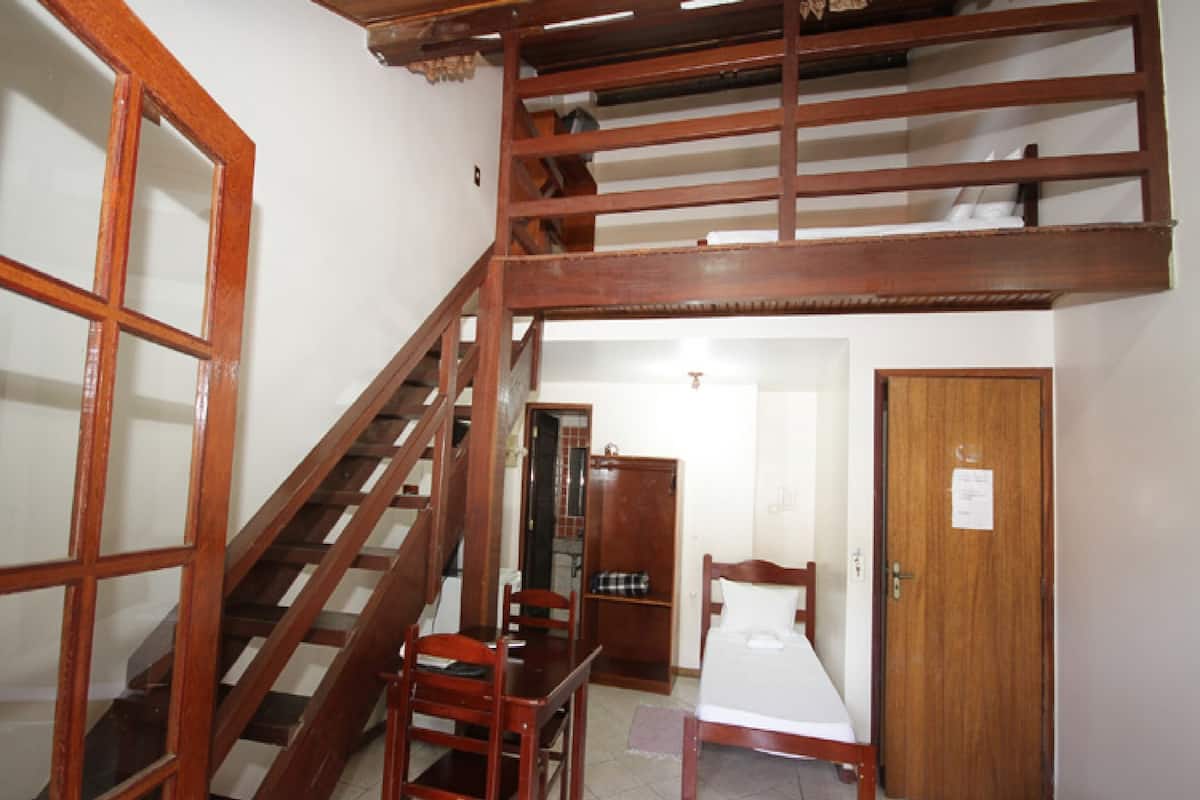 Una habitación con una escalera de madera, una cama, una silla y un armario.
