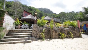 A beachside resort with a thatched-roof hut, a staircase leading to a beach, and lush greenery. - Pousada Angra Bella (Angra dos Reis)