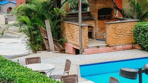 A villa with a swimming pool, outdoor seating, and a brick barbecue area. - Pousada Angra Bella (Angra dos Reis)