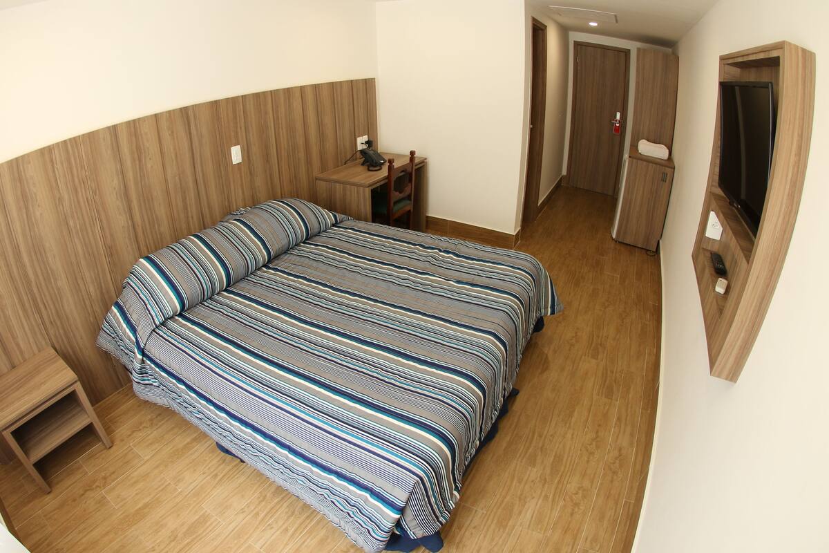 Minibar, escritorio, cortinas blackout y tabla de planchar con plancha