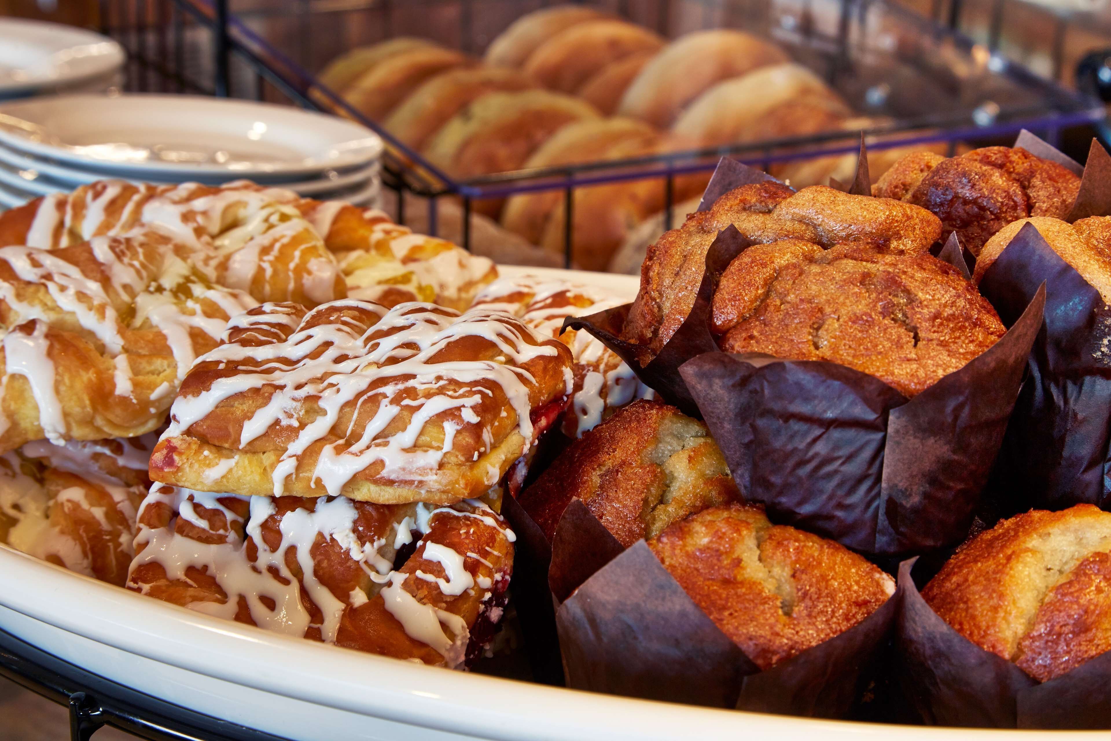 Diversa variedad de productos de pastelería, como pasteles y muffins, exhibidos en una panadería.