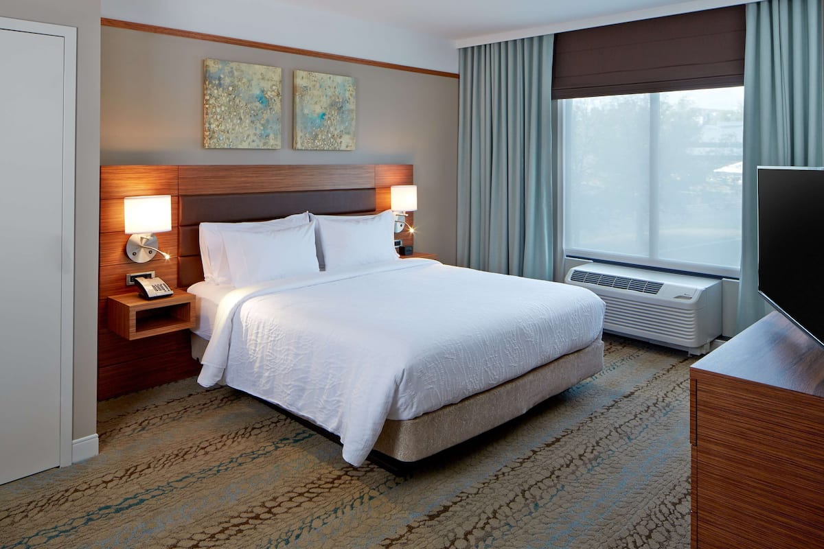 A hotel room with a large bed, two bedside lamps, a telephone, and a television.