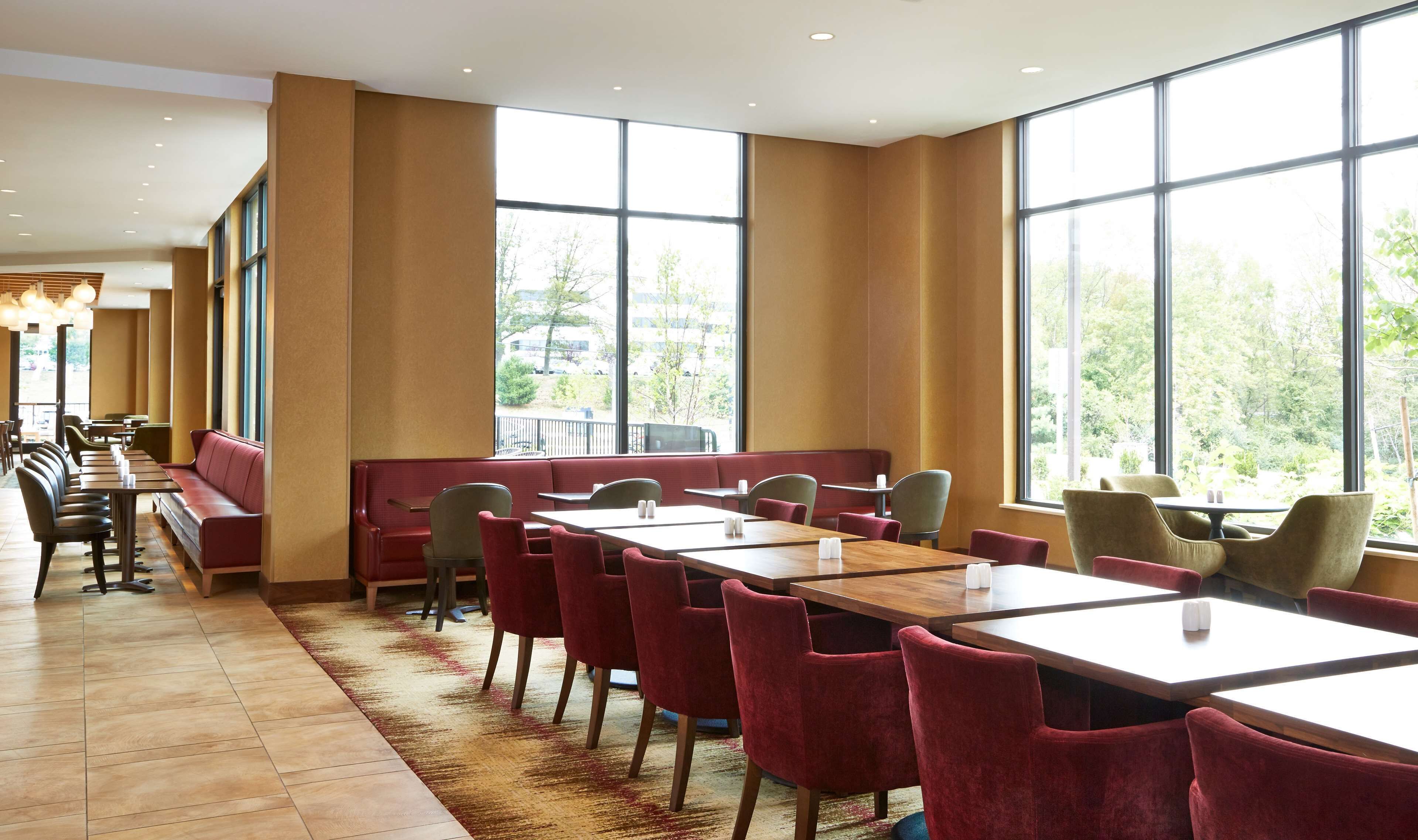 A spacious dining area with high ceilings, large windows, and a mix of booth and table seating.
