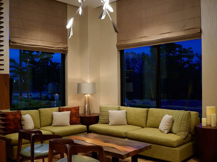 A modern living room with a green sofa, wooden coffee table, and a chandelier.