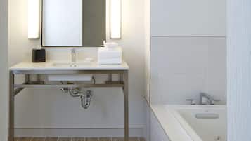 A modern bathroom with a white sink, a large mirror, and a bathtub.