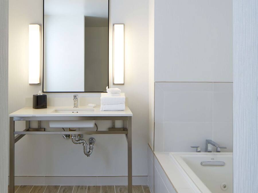 A modern bathroom with a white sink, a large mirror, and a bathtub.